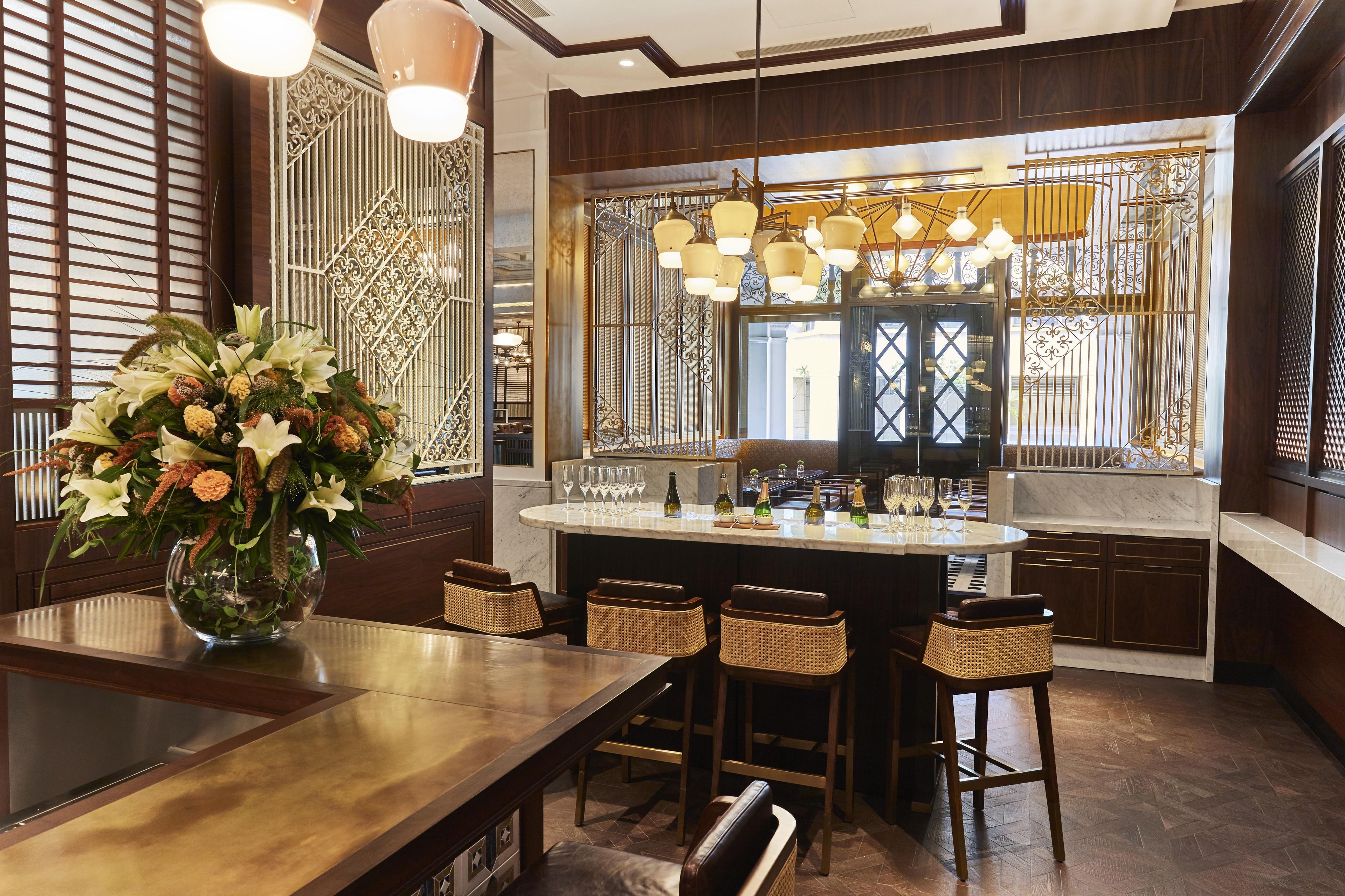 Una cocina moderna con una isla central, taburetes de bar y un jarrón decorativo con flores.