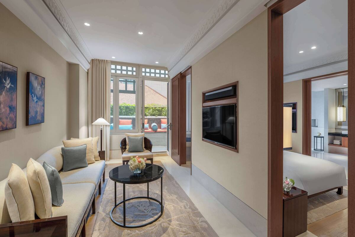 A modern living room with a sofa, a round coffee table, and a TV mounted on the wall.