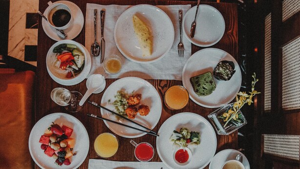 A dining table with various dishes, utensils, and a person holding chopsticks. - The Capitol Kempinski Hotel Singapore (Singapore)