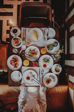 Una mesa de comedor con diferentes platos, utensilios y una persona sosteniendo palillos.