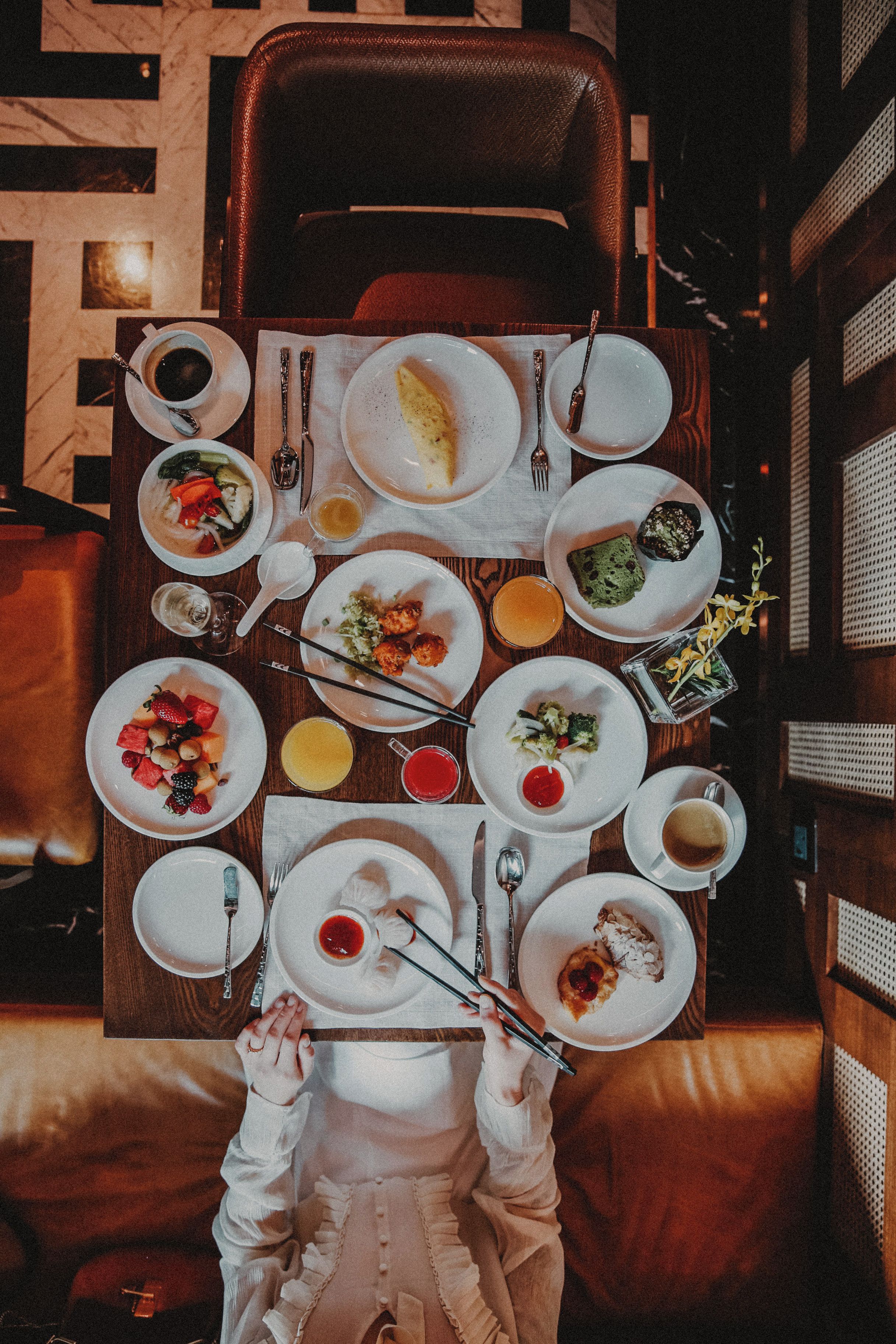 Un tavolo da pranzo con diversi piatti, utensili e una persona che usa le bacchette.