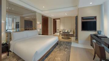 Habitación de hotel con una cama grande, un escritorio con una silla, un televisor y un espejo.