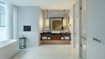 Une salle de bain moderne avec un grand miroir, une baignoire et un meuble-lavabo doté d’un plan de travail en marbre.