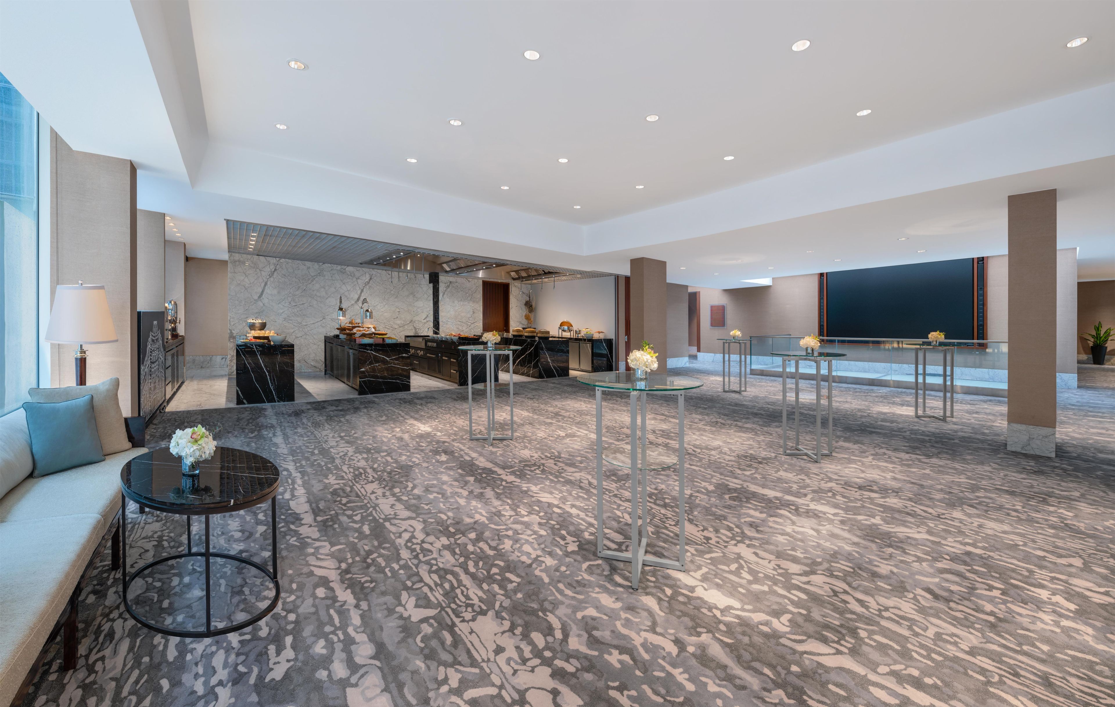 A spacious lobby with a marble floor, seating areas, and a reception desk.