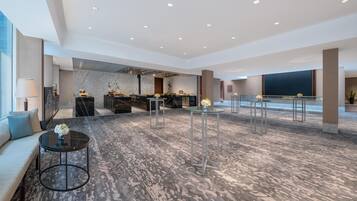 A spacious lobby with a marble floor, seating areas, and a reception desk.