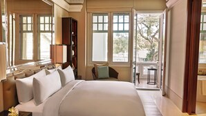 A spacious bedroom with a large bed, a nightstand, a bookshelf, and a view of the outdoors through a large window. - The Capitol Kempinski Hotel Singapore (Singapore)