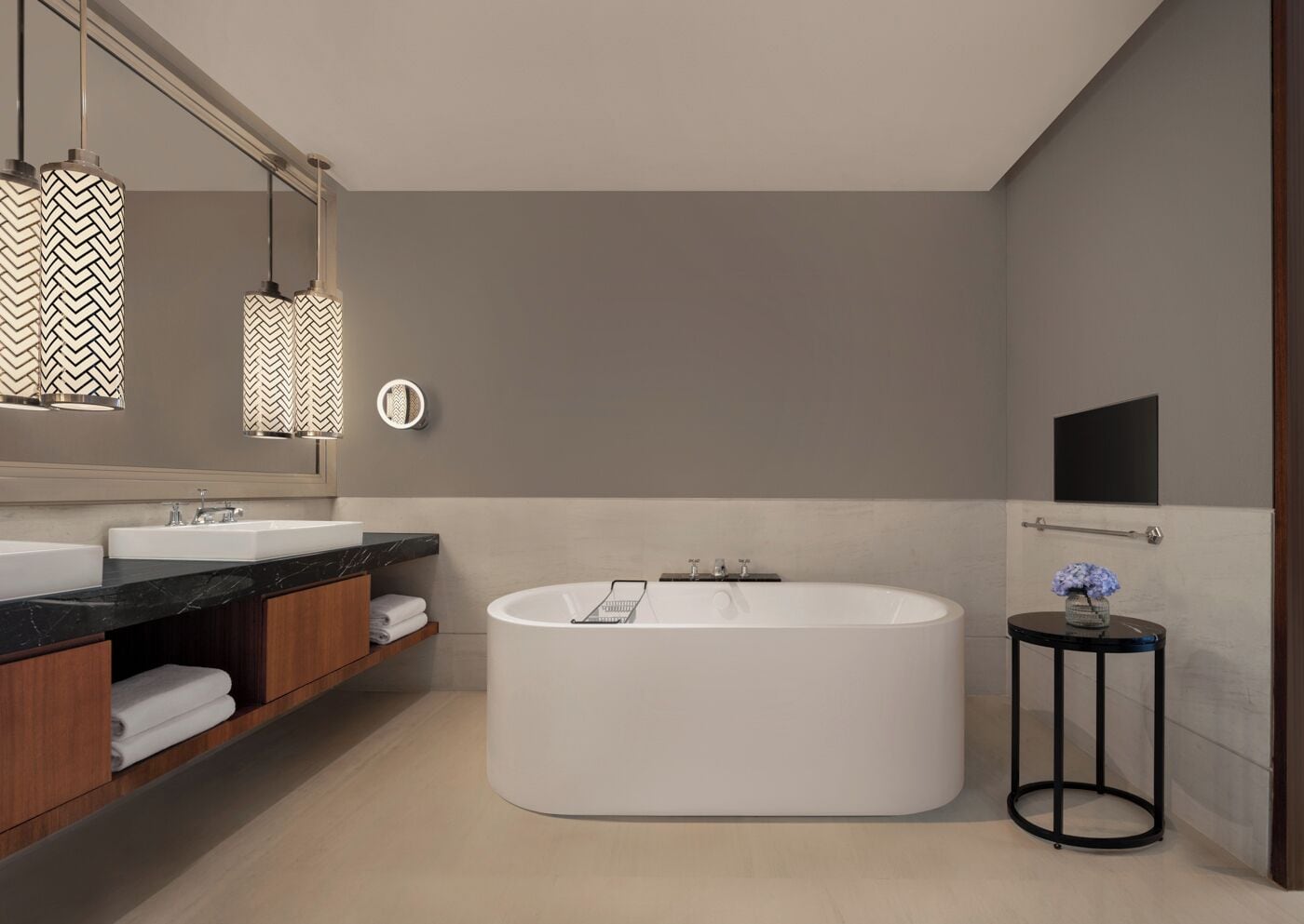 A modern bathroom with a freestanding bathtub, a large mirror, and pendant lights.
