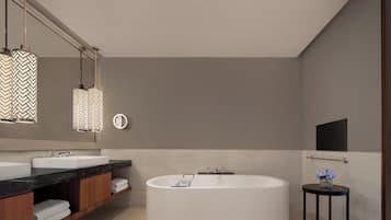 A modern bathroom with a freestanding bathtub, a large mirror, and pendant lights.