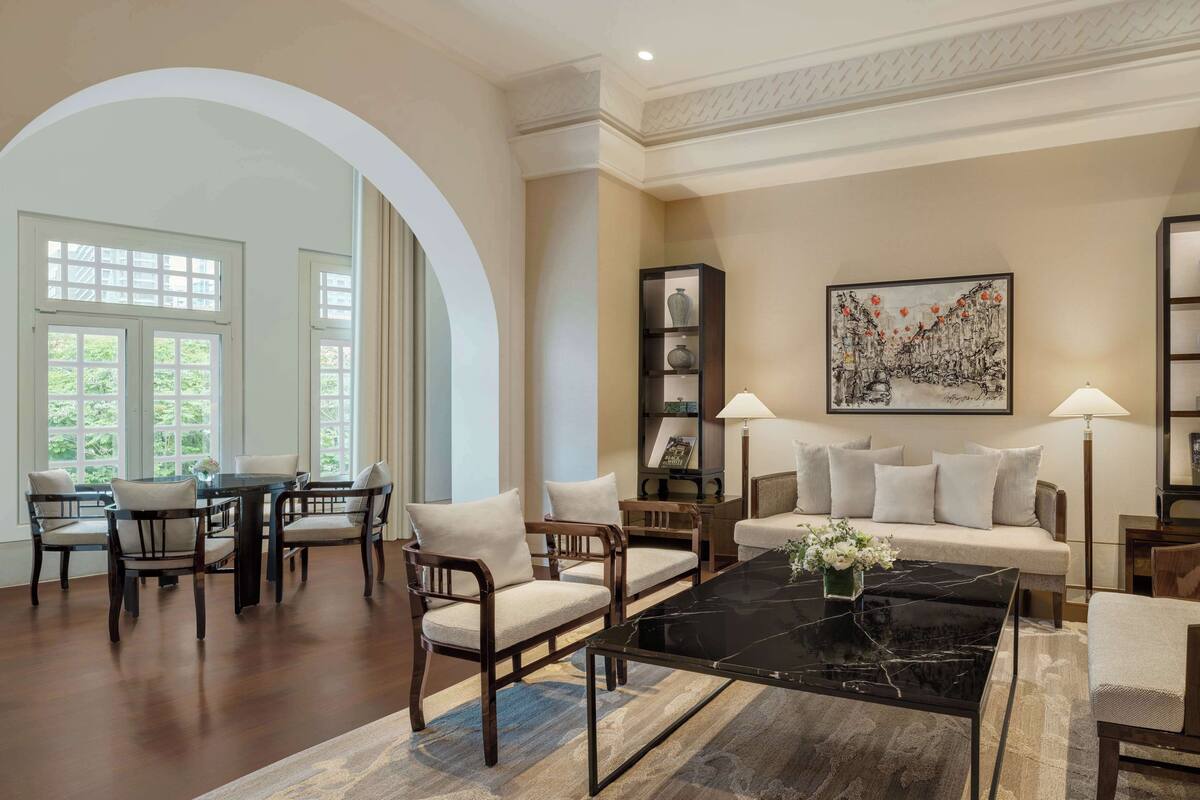 A spacious living room with a dining area, a sofa set, a coffee table, and a bookshelf.