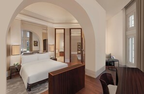 A hotel room with a large bed, a wooden desk, a chair, a mirror, and a view of the outside through a window. - The Capitol Kempinski Hotel Singapore (Singapore)