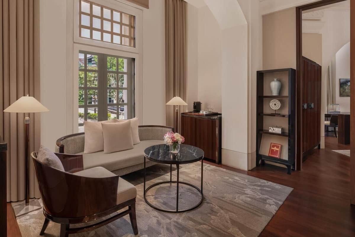 A modern living room with a sofa, two armchairs, a coffee table, and a bookshelf.
