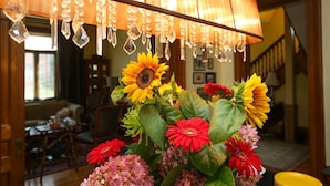 A room with a chandelier, a floral arrangement, and a staircase in the background. - Danby House (Grey Highlands)