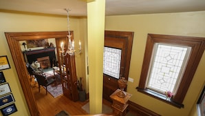 A staircase with wooden railings leading to a living area with a fireplace, a chandelier, and a dining area with a rug. - Danby House (Grey Highlands)