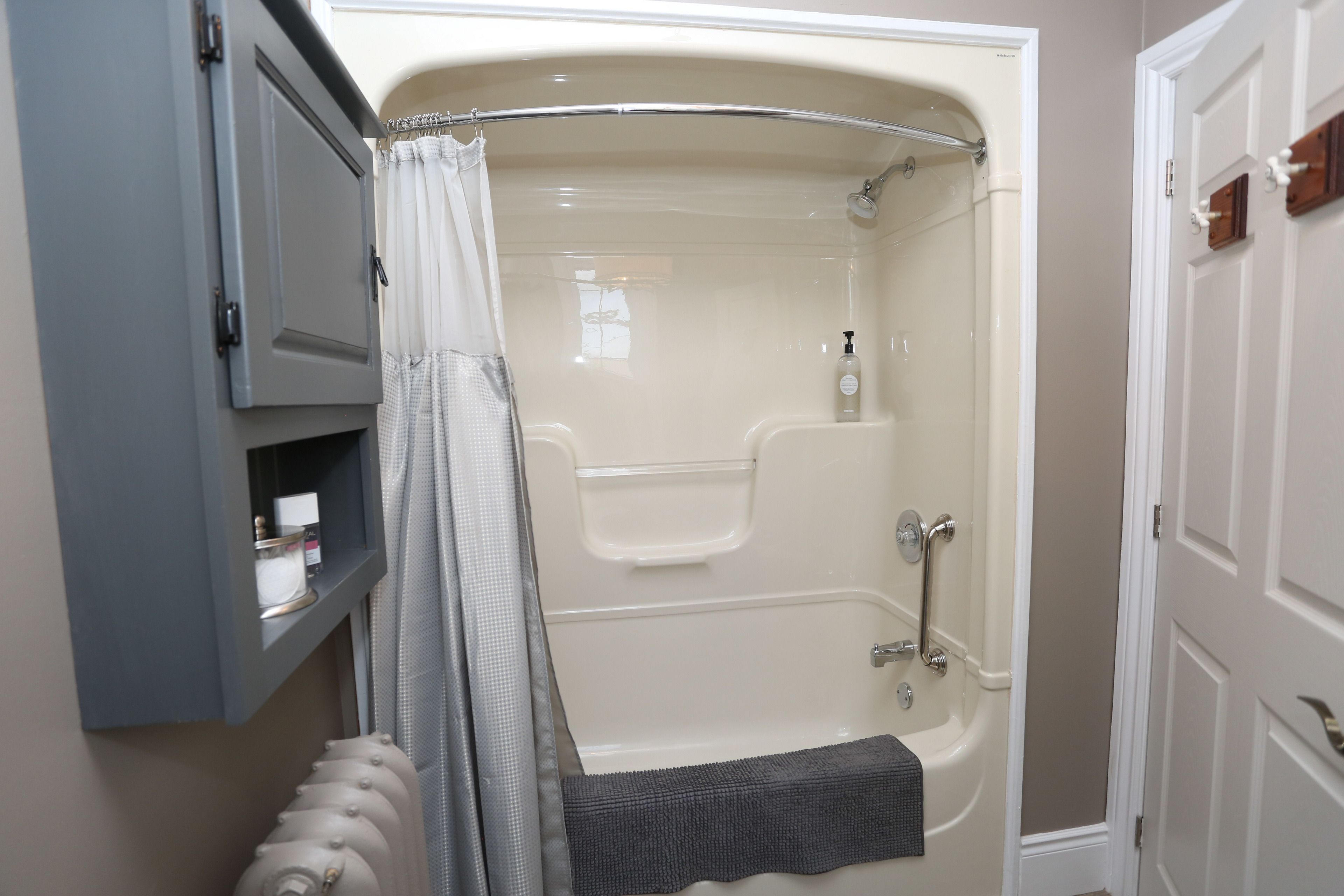 A bathroom with a bathtub, a shower, a towel rack, and a shelf with toiletries.