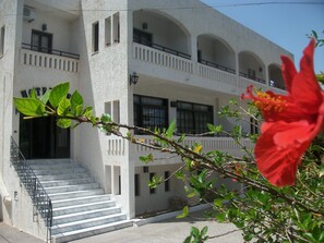 A building with multiple balconies, a staircase leading to the entrance, and a red flower in the foreground. - Efi Hotel (Hersonissos)