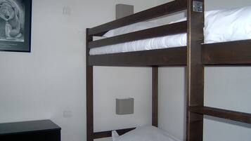 Una cama individual superpuesta en una habitación con un escritorio pequeño y un cuadro en la pared.