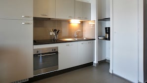 A modern kitchen with stainless steel appliances, white cabinetry, and a built-in oven. - Apart-Hôtel Le Pic de l'Ours (Font-Romeu-Odeillo-Via)