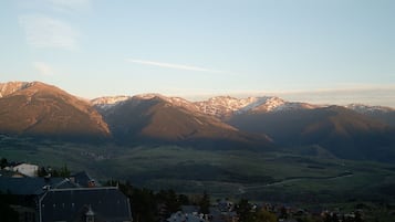 Un paysage montagneux, avec des sommets enneigés en arrière-plan et une vallée parsemée de bâtiments au premier plan.