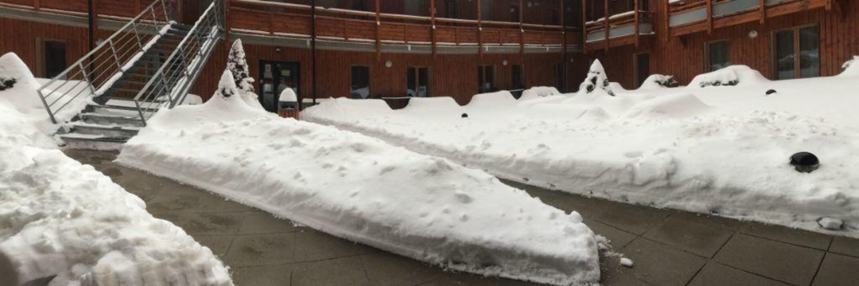 A snow-covered courtyard with a staircase leading to a building entrance.