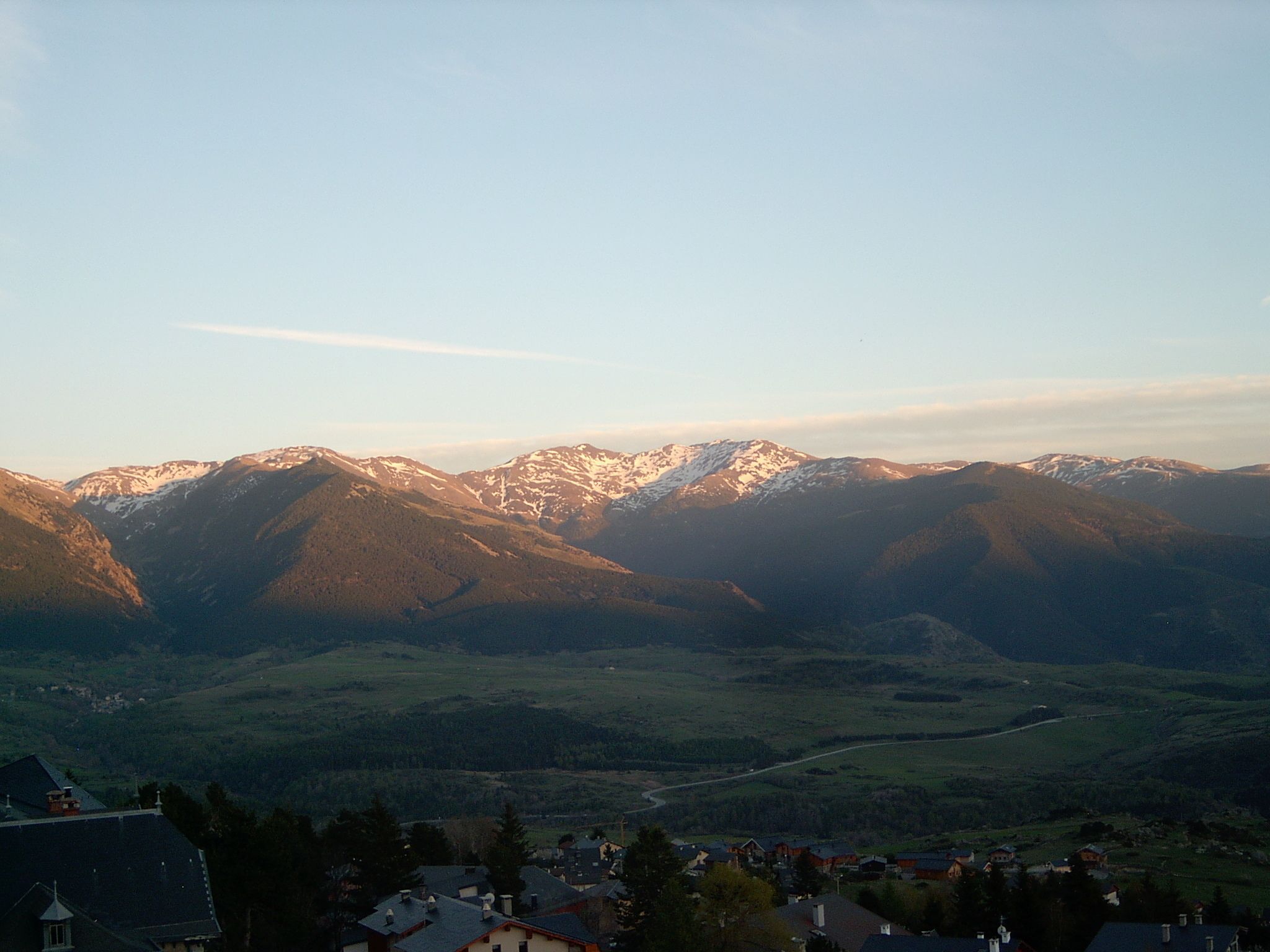 A mountain landscape with a valley and a small settlement at the base.