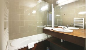 Un baño moderno con ducha compartimentada por vidrio, una bañera y dos lavamanos con espejos.