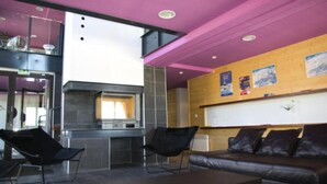 A modern interior with a kitchen area, a sofa, and a seating area. - Apart-Hôtel Le Pic de l'Ours (Font-Romeu-Odeillo-Via)