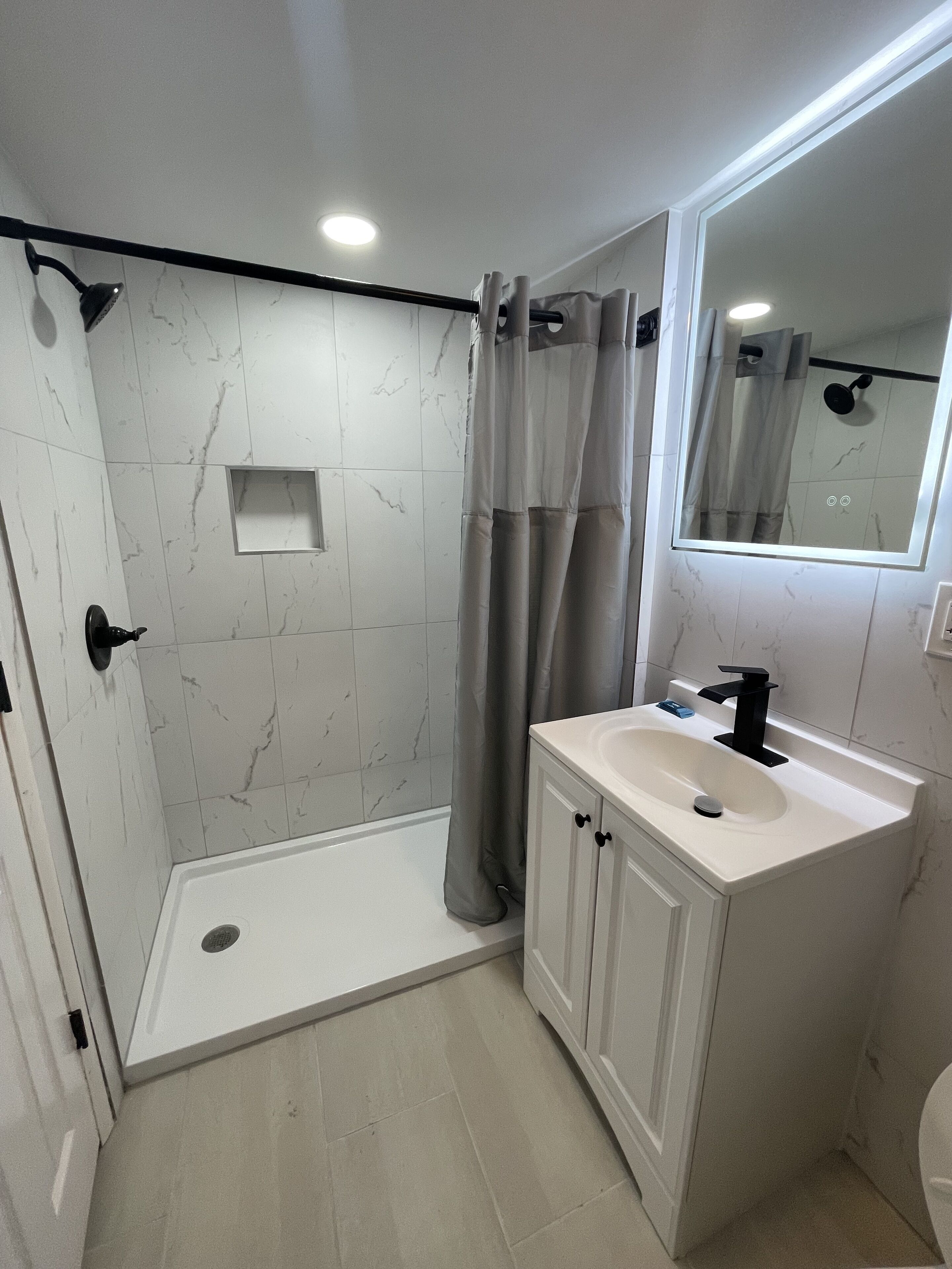 Een moderne badkamer met een ruime douche, een wastafelmeubel en een spiegel.