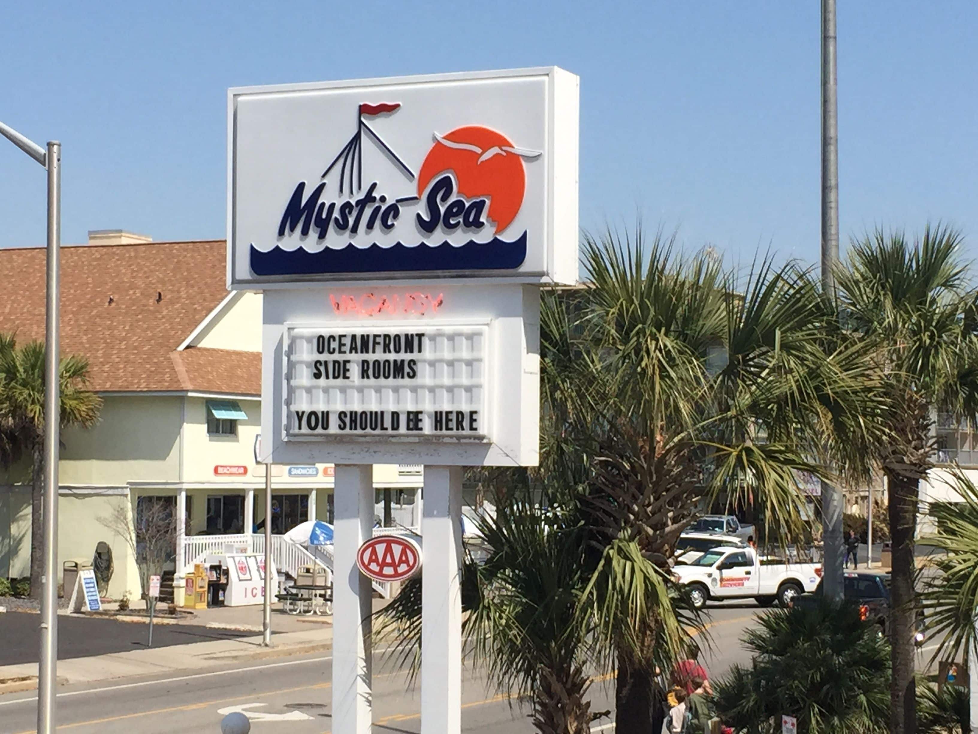 A sign for Mystic Sea with a beachside view.