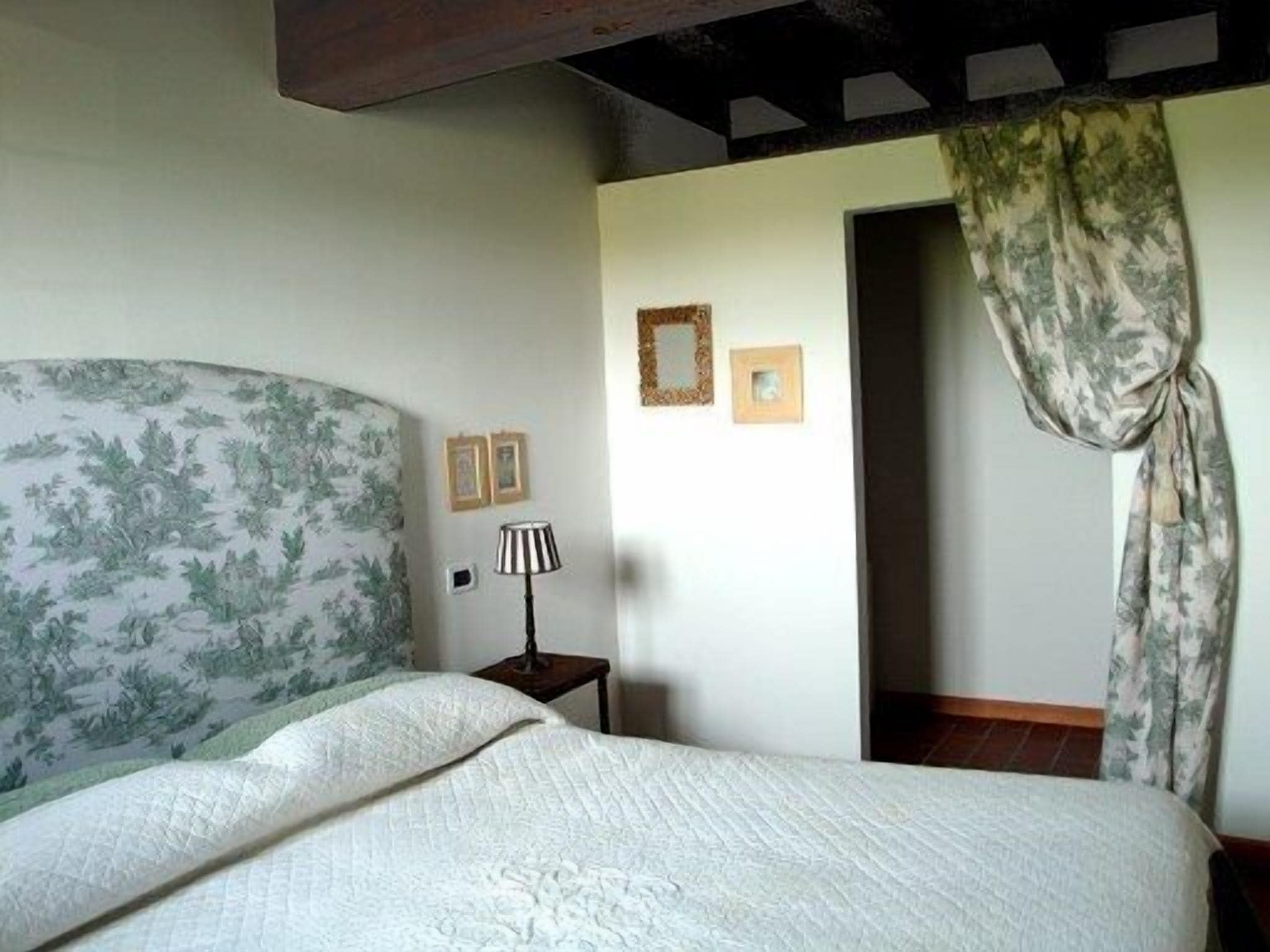Une chambre à coucher avec un lit, une lampe et une porte avec un rideau.