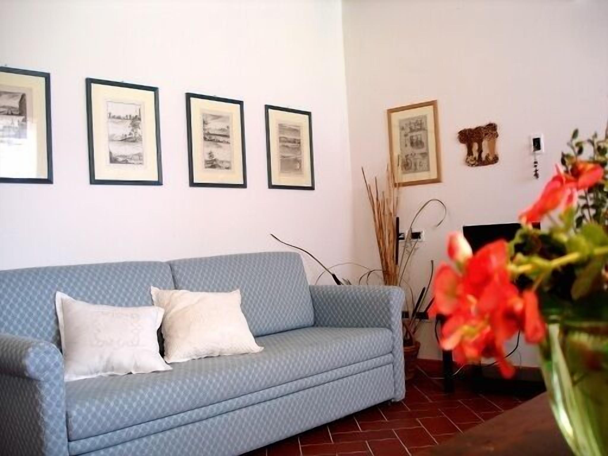 A room with a blue sofa, white cushions, and framed artwork on the wall.