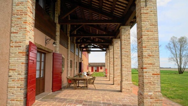A covered outdoor area with brick walls and a wooden ceiling, featuring a table and chairs. - Agriturismo Ca' Lealtà (Caorle)