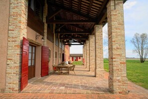 Un espacio al aire libre cubierto con paredes de ladrillo y techo de madera, con una mesa y sillas.