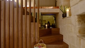 A staircase with wooden steps leading to a loft area, a stone wall, and a small plant on a shelf. - Le Malve Cave Retreat (Matera)