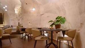 A dining area with a stone wall, a table with chairs, and a potted plant. - Le Malve Cave Retreat (Matera)