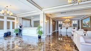 Een hotel lobby met een receptiebalie, een zithoek en een bar.