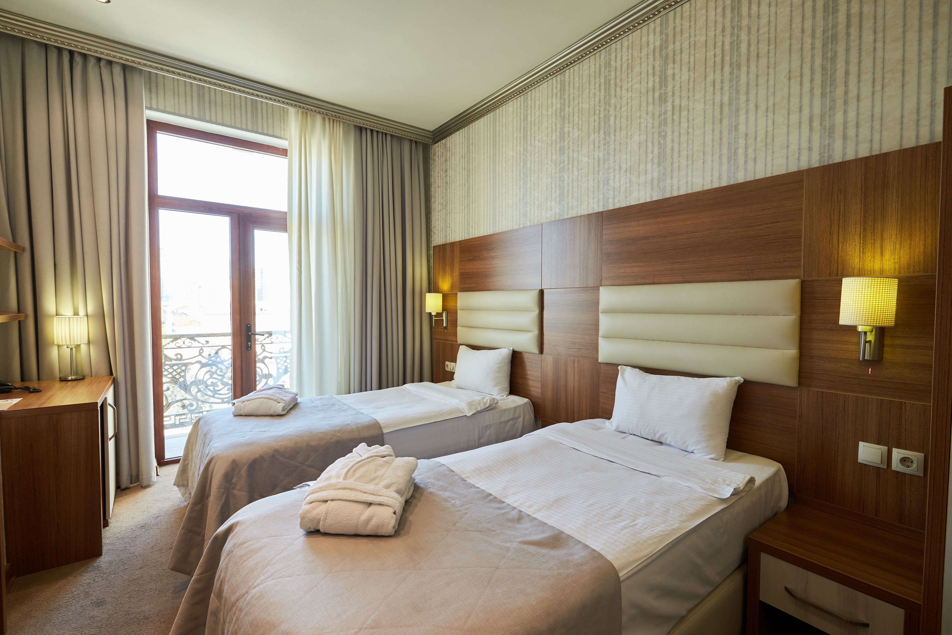 Habitación de hotel con dos camas, un escritorio y un balcón.