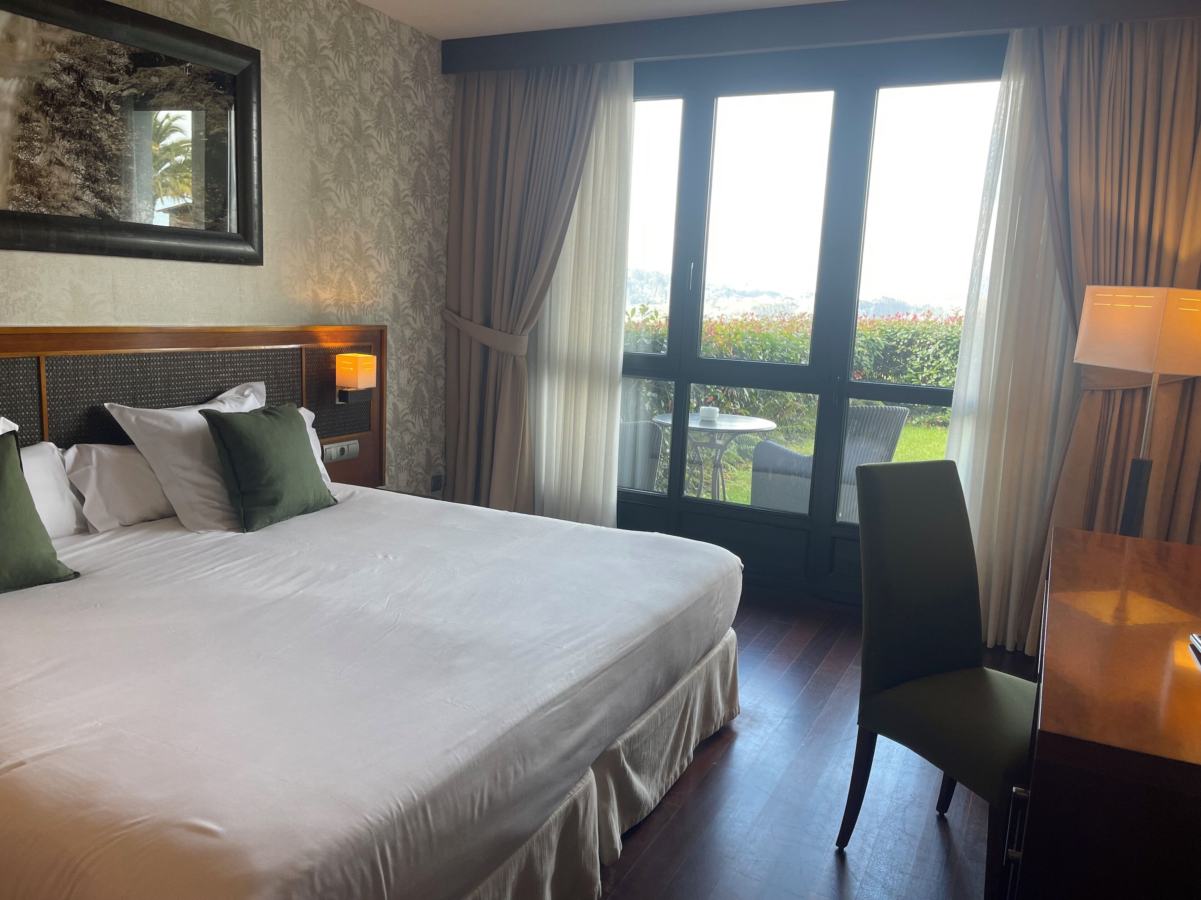 Een hotelkamer met een groot bed, een bureau en uitzicht op de omgeving.