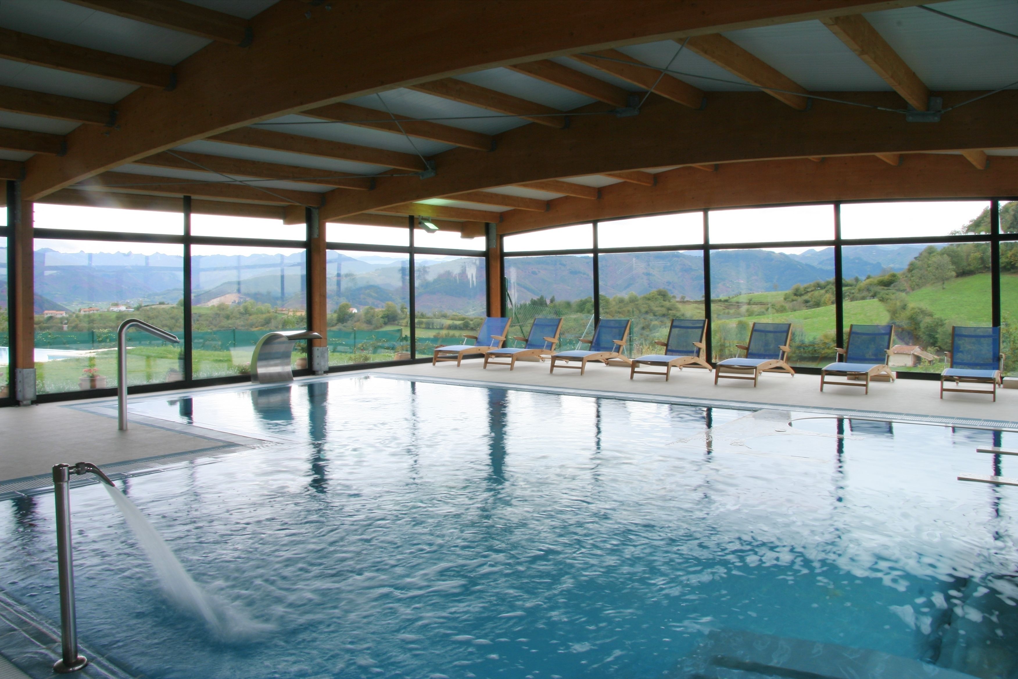 Una piscina interior con vistas despejadas a montañas a través de amplios ventanales.