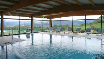Una piscina interior con vistas despejadas a montañas a través de amplios ventanales.