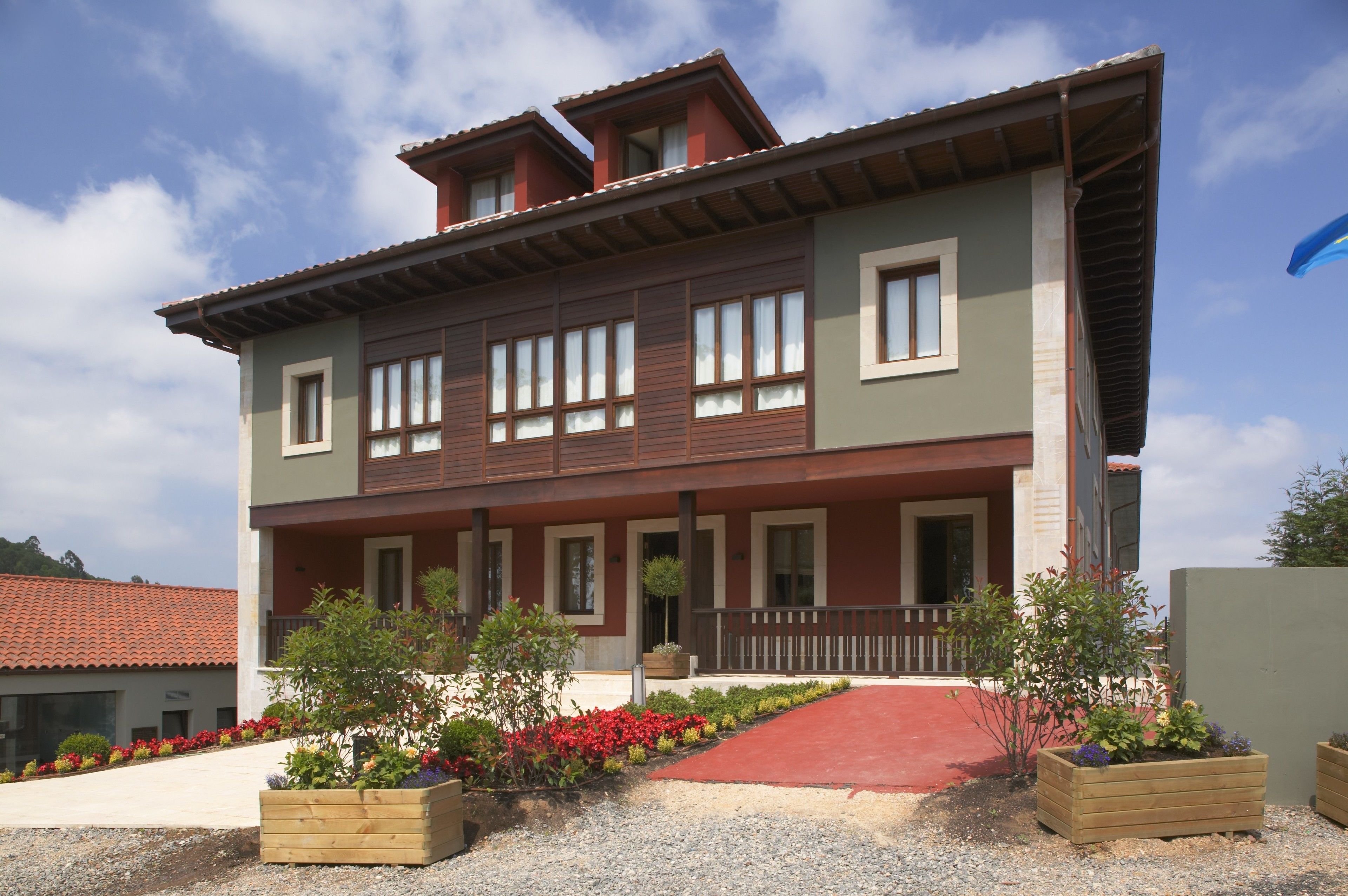 A two-story building with a red-tiled roof, multiple windows, and a red carpet leading to the entrance.