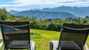 Dos sillas metálicas mirando a un paisaje montañoso con cielo despejado.