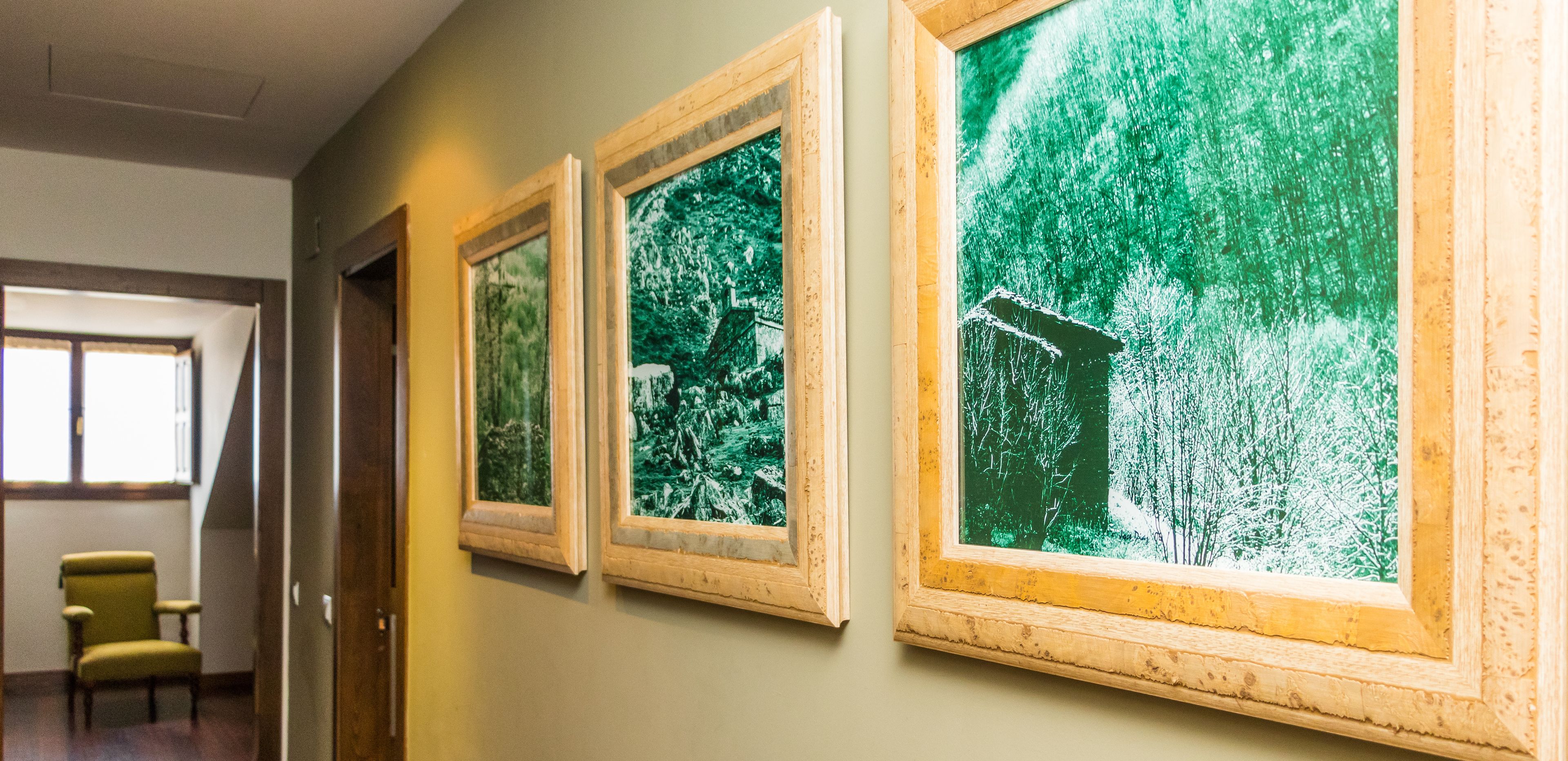 A hallway with three framed pictures of a forest scene on the wall.