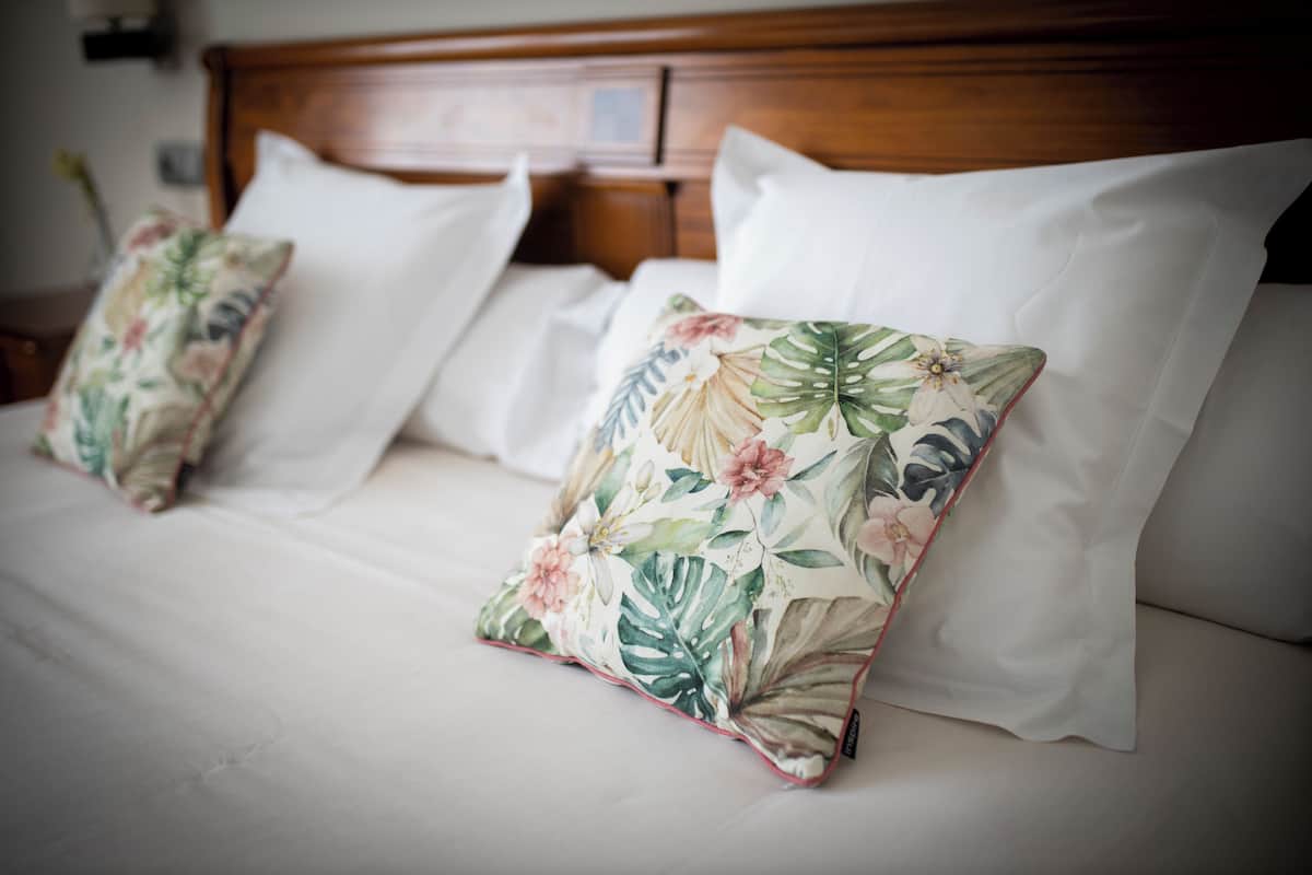 Un lit avec du linge de lit blanc et des oreillers à motifs floraux.