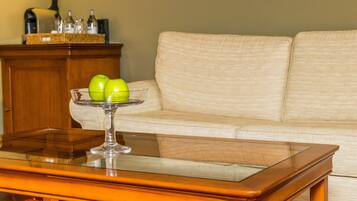 A glass table with a clear glass top, a wooden side table, and a beige sofa in the background.