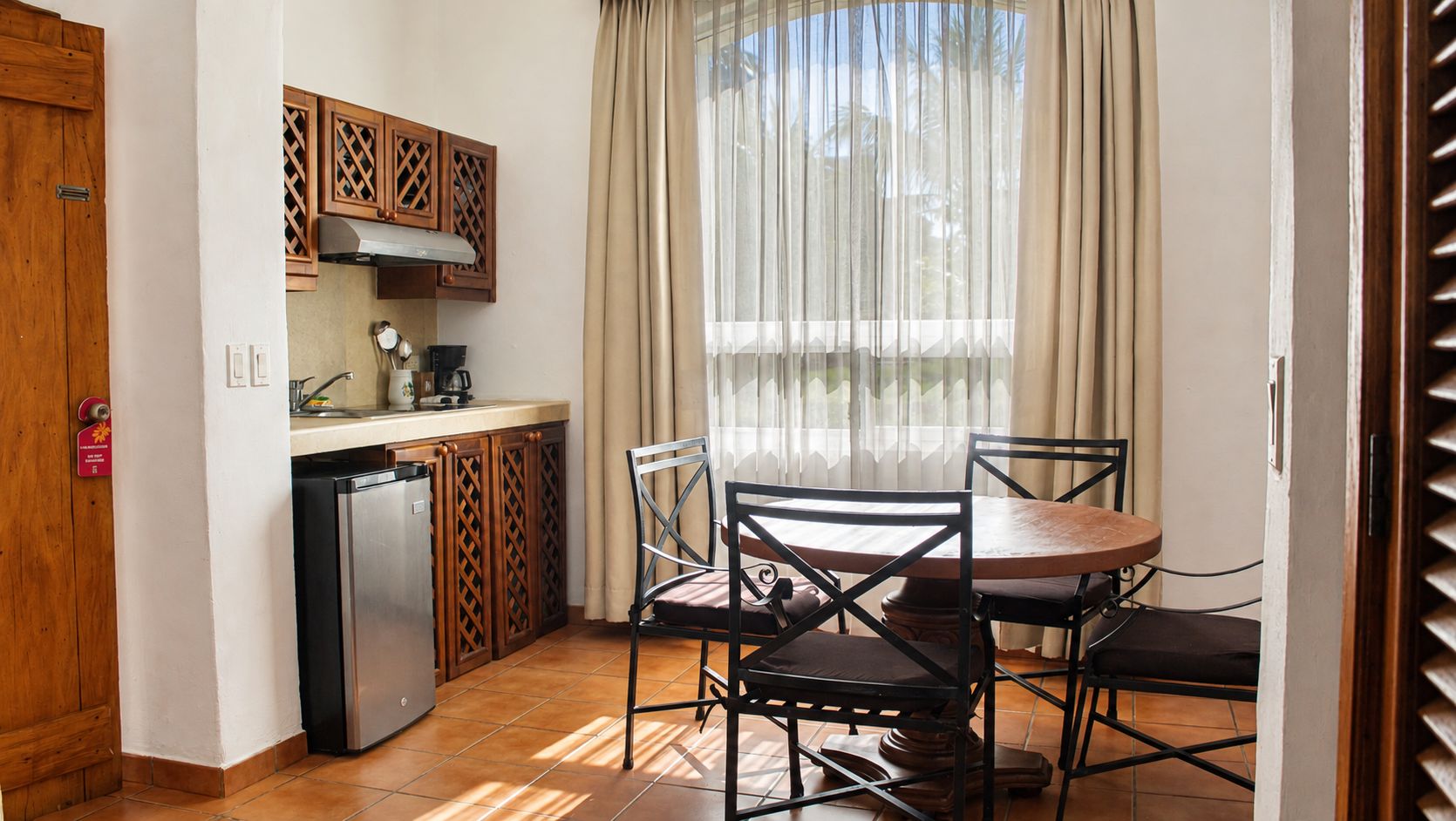 Une cuisine compacte équipée d’un réfrigérateur, d’un évier et d’une cuisinière. On y trouve également une table à manger avec quatre chaises.