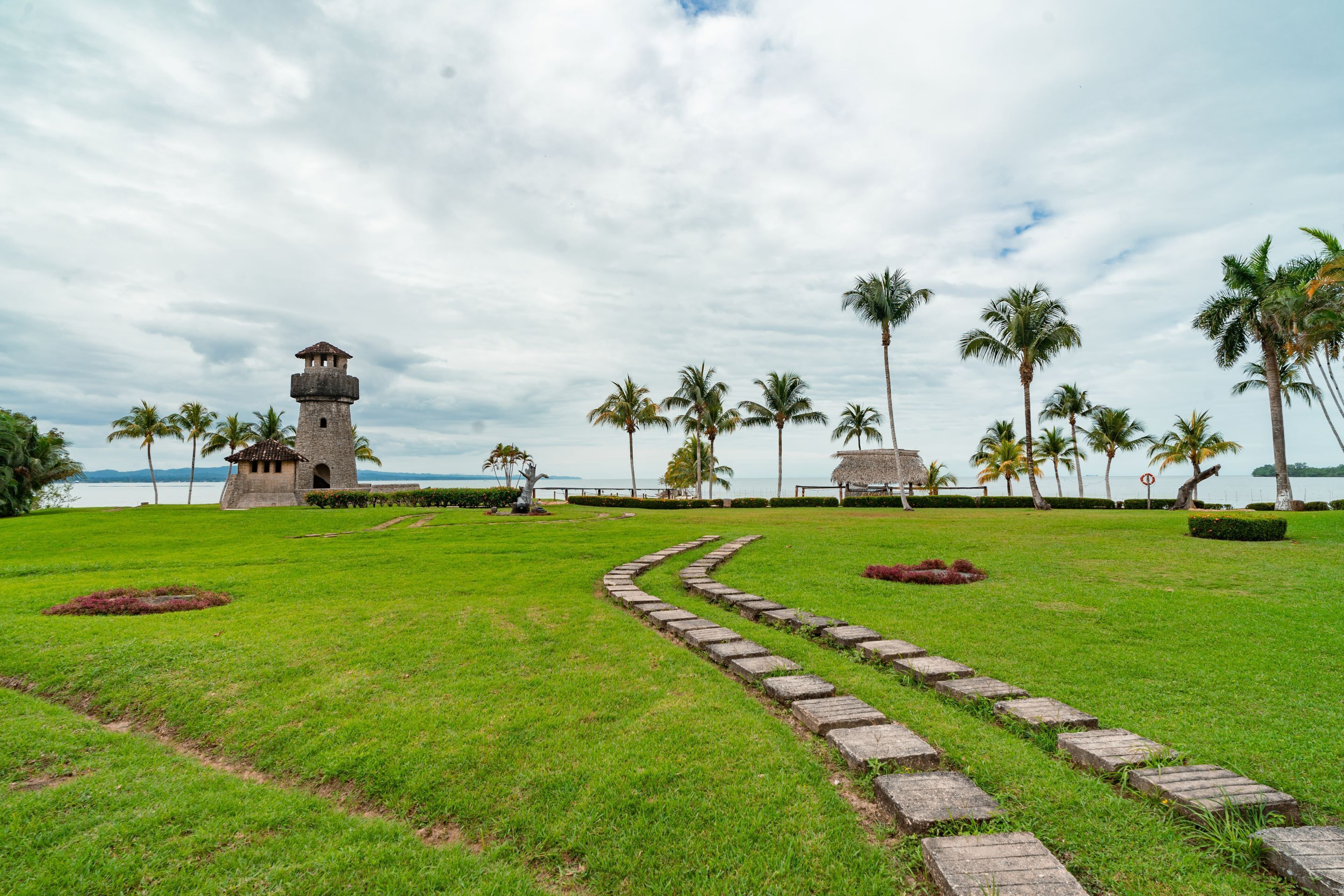 A grassy area with a stone pathway leading to a tower structure.