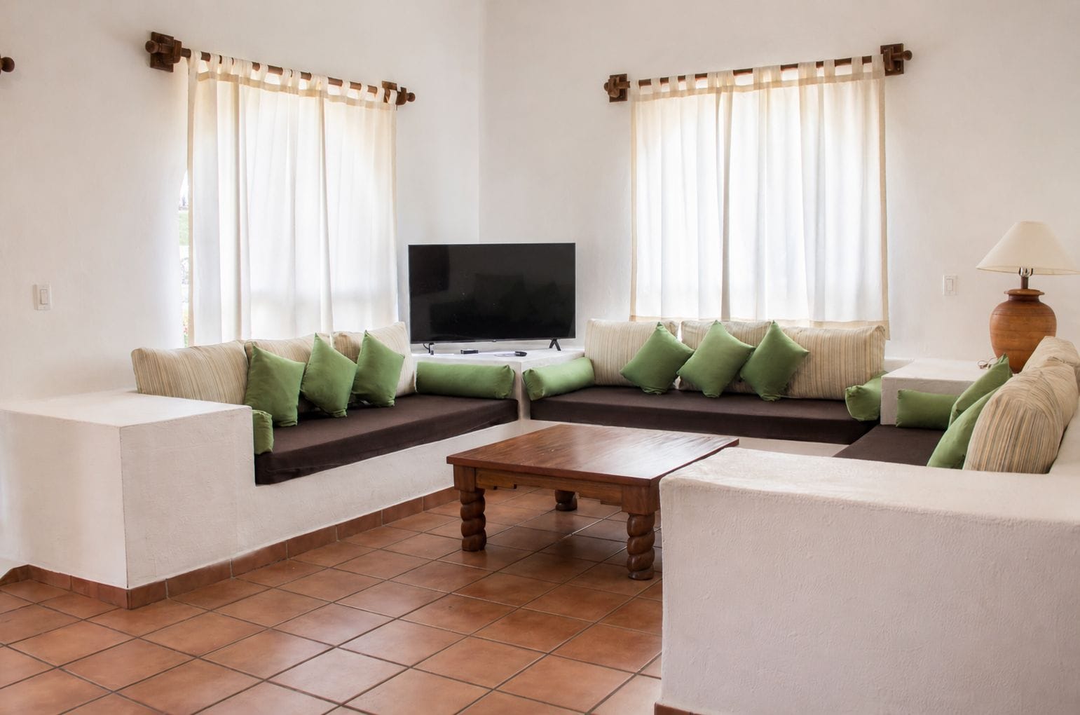 A living room with a sofa set, a coffee table, a flat-screen TV, and a lamp.