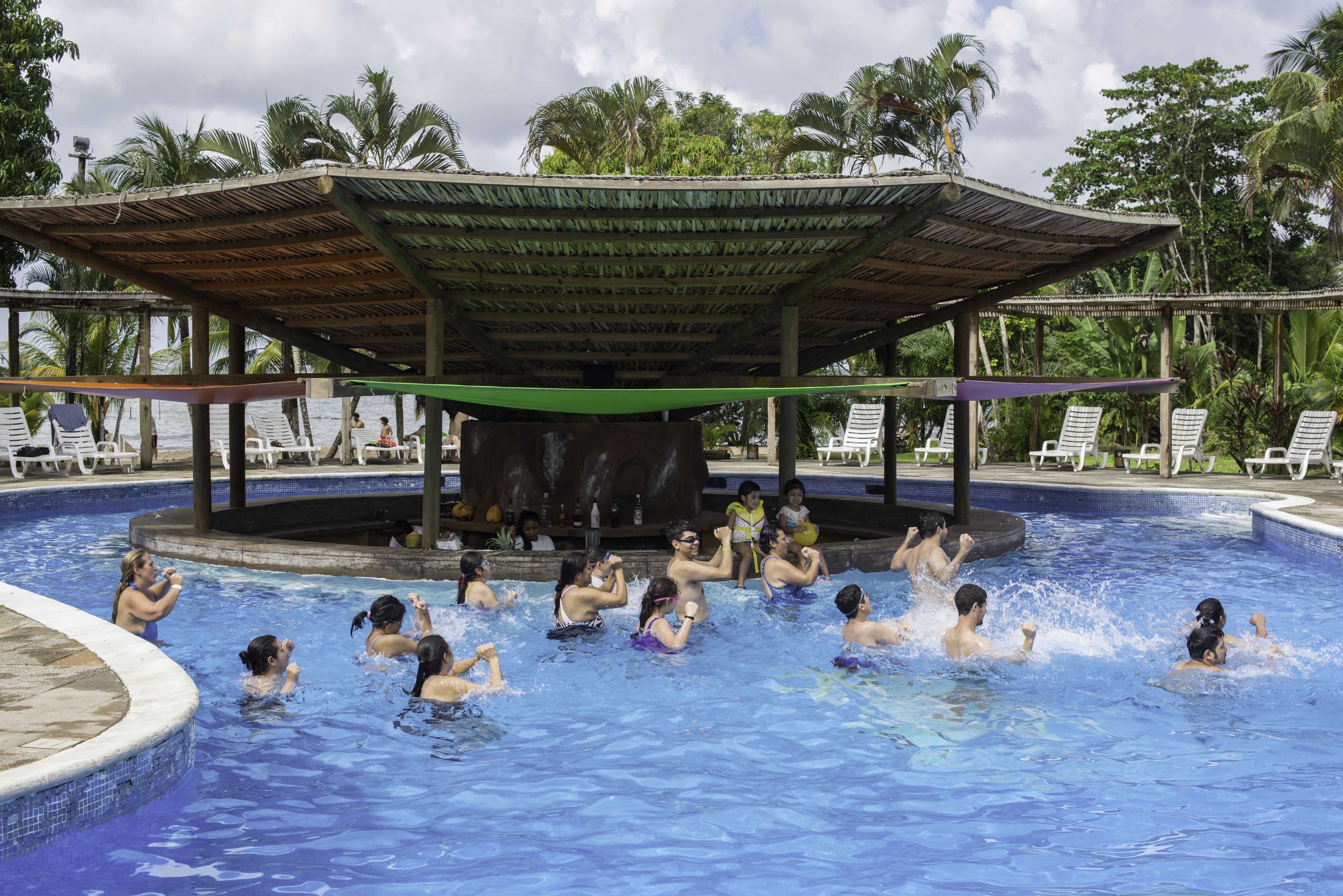 Una piscina con zona cubierta y sillas de descanso alrededor.