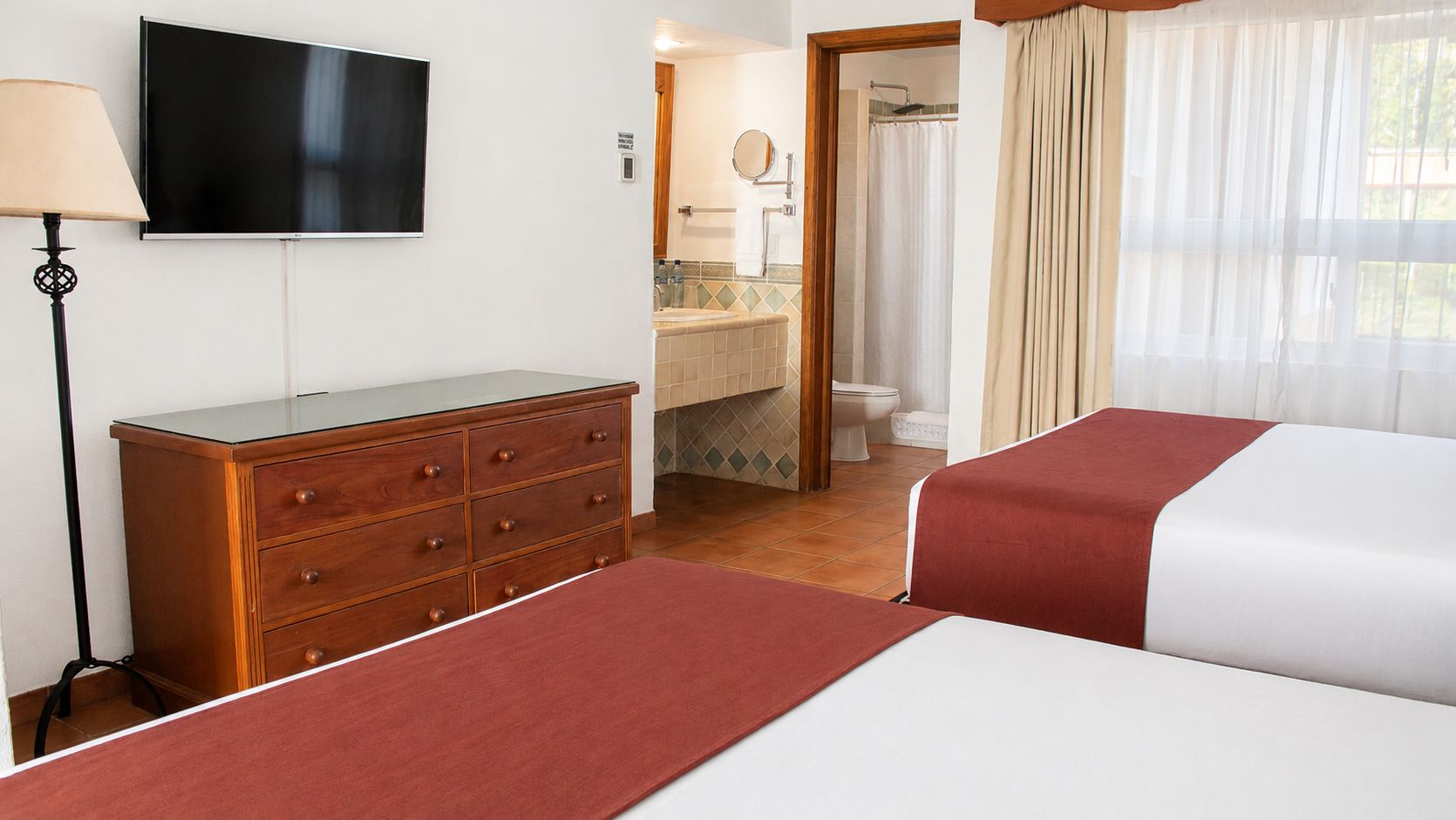 Een hotelkamer met een bed, een kaptafel, een televisie en een badkamer zichtbaar door een geopende deur.