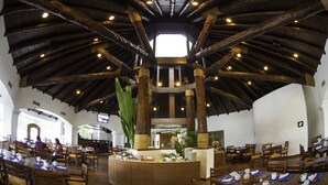 Un vaste espace dédié à la salle à manger, avec de hautes poutres en bois et un îlot central doté de sièges.